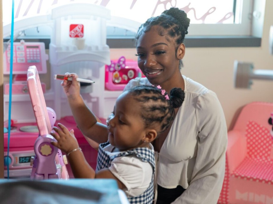 Toddler with mother looking on
