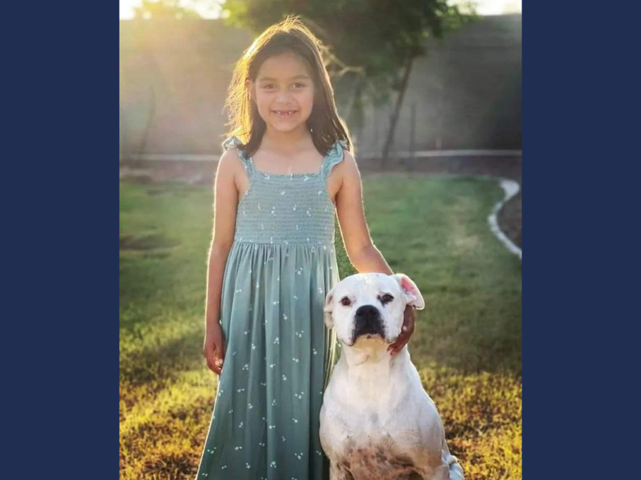 Young girl standing next to white dog