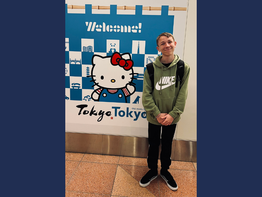 Teen boy next to Hello Kitty sign