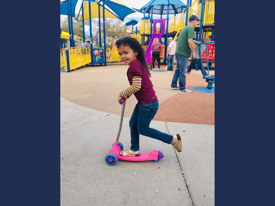 Girl on pink scooter at playground