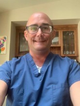 Selfie of doctor in blue scrubs and glasses
