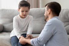 Father and son holding hands, sitting on couch