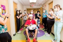 Patient in wheelchair celebrating as they leave hospital