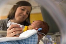 Mother feeding infant in incubator