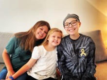 3 siblings smile together on couch