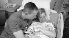 Mother and father holding infant in hospital bed