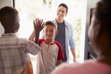 Two boys high-fiving with dad in the background