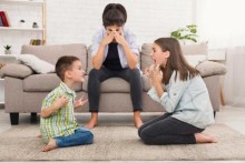 Children arguing in front of mom on couch