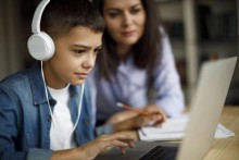 Boy working on laptop while mother looks on