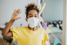 Masked kid waving at camera