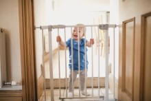 Toddler standing behind a baby gate
