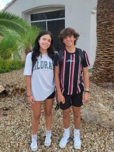 Teenage boy and girl standing outside home, smiling