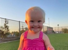 Toddler in pink top smiling at camera