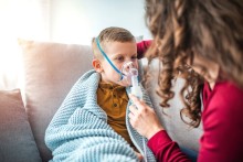 Child in blanket wearing a breathing treatment mask