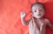 Infant with adult hand on their chest