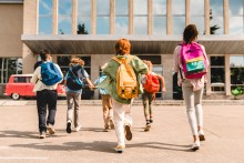 Kids wearing backpacks in front of school