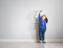 Child measuring self against ruler on wall