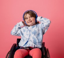 Child in wheelchair, wearing blue headphones