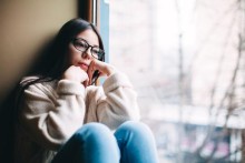 Pensive teen sitting next to window