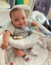 Baby in play seat, smiling at camera