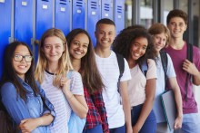 Group of smiling teens standing in front of lockers