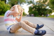 Young child on floor, holding his head