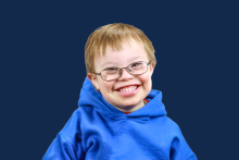 Boy in glasses and blue sweatshirt, smiling at camera