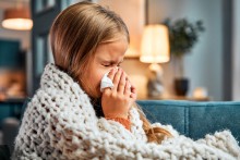 Young girl blowing her nose