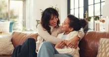 Mother hugging daughter on couch