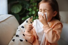 Toddler sneezing into tissue
