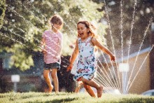 Children playing in yard sprinkler