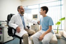 Male doctor talking to adolescent boy