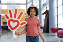 Girl in pink shirt, heart hand logo sign