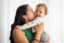 Mother holding & kissing baby